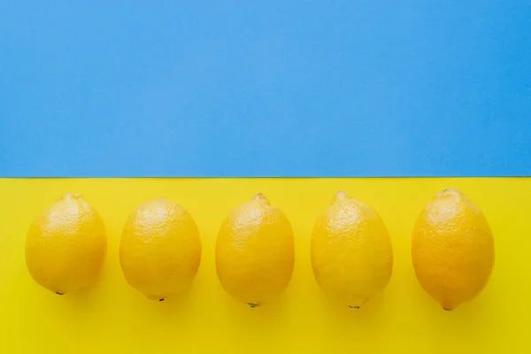 Vista Superior Fila Limones Sobre Fondo Azul Amarillo — Foto de Stock