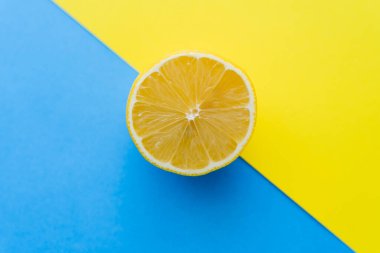 Top view of cut lemon on blue and yellow background clipart