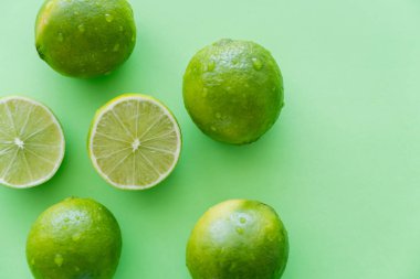 Bütünün üst görünümü ve yeşil arkaplanda su damlalarıyla limonları kes