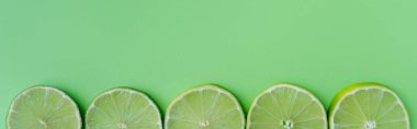 Top view of sliced lime on green background, banner 