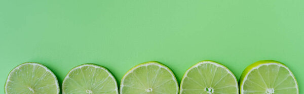 Top view of sliced lime on green background, banner 
