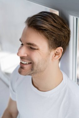 Yüksek açılı genç adam gözleri kapalı gülümsüyor.