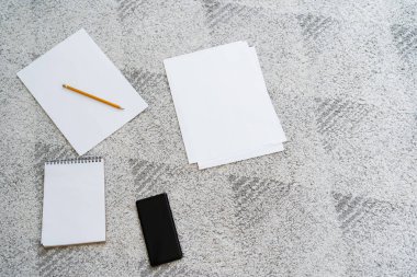 Boş kağıtların üst görünümü, kalem, defter ve cep telefonu ile gri zemin üzerinde boş ekran