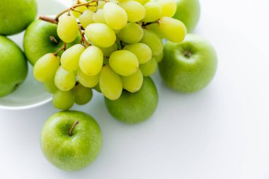 top view of green and ripe apples near grapes on white