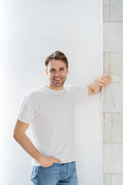 Joven Feliz Hombre Pie Con Mano Bolsillo Jeans Cerca Pared — Foto de Stock