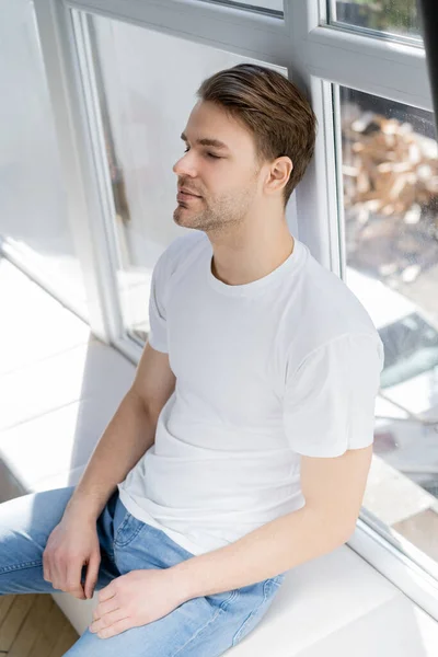 Joven Camiseta Blanca Sentado Alféizar Ventana Con Los Ojos Cerrados — Foto de Stock