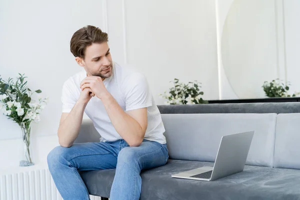 Junger Mann Sitzt Auf Couch Wohnzimmer Und Schaut Auf Laptop — Stockfoto