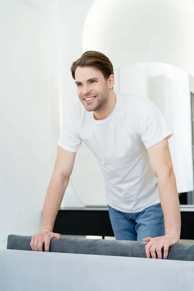 Beyaz Tişörtlü Genç Adam Oturma Odasında Dururken Gülümsüyor — Stok fotoğraf