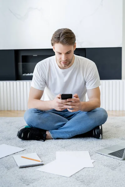 Man Sitter Golvet Med Korsade Ben Och Meddelanden Smartphone Nära — Stockfoto