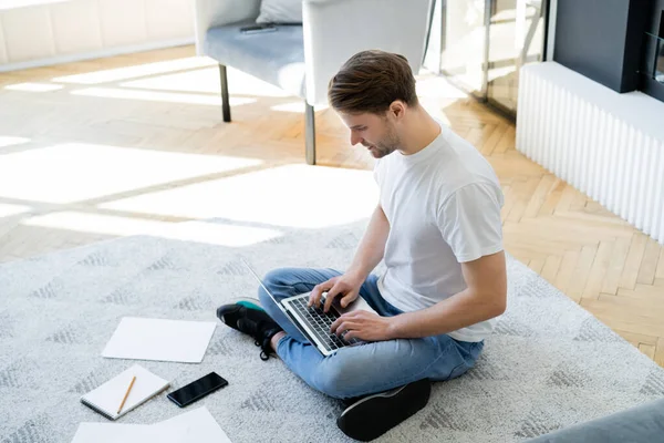 Hoge Hoek Van Mens Zitten Vloer Met Gekruiste Benen Typen — Stockfoto