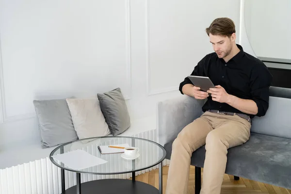 Ung Man Använder Digital Tablett Nära Soffbord Vardagsrummet — Stockfoto