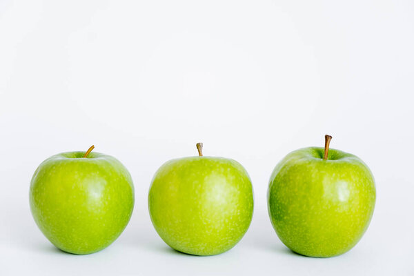 row of green and ripe apples on white