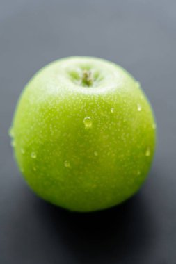 close up view of green and fresh apple with water drops on black 