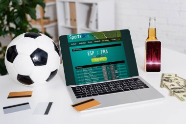 KYIV, UKRAINE - 4 Şubat 2022: futbol topu, kredi kartları ve akıllı telefon yanında dolar ve spor siteli dizüstü bilgisayar