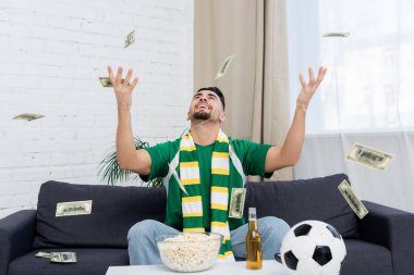 Heyecanlı bahisçi futbol topu, bira ve patlamış mısır yakınlarında para kusuyor.