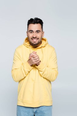 Elleri sımsıkı bağlı neşeli bahisçi gri kameraya bakıyor.