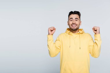 excited bookmaker showing win gesture while looking at camera isolated on grey