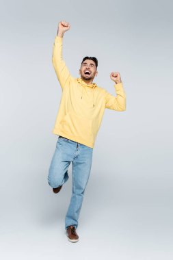 full length of gambler screaming and showing rejoice gesture on grey