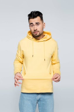 Kafası karışmış kumarbaz gri üzerinde boş cep gösteriyor