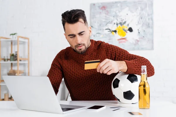 Serious Bookmaker Holding Credit Card Soccer Ball Laptop Beer — Φωτογραφία Αρχείου