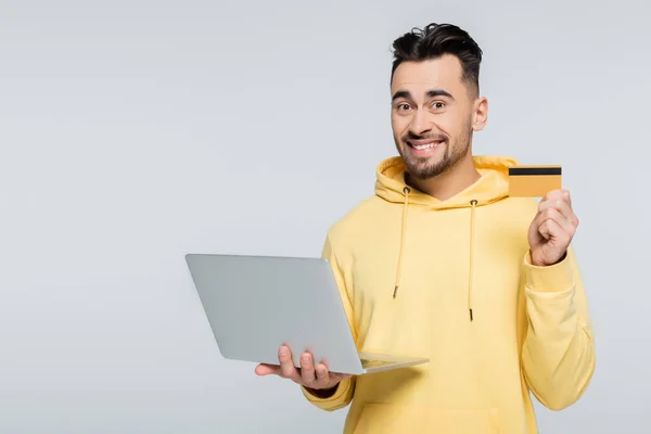 Pleased Man Holding Credit Card Laptop While Looking Camera Isolated — 图库照片