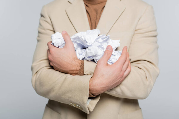 partial view of critic in beige blazer holding plenty of crumpled paper isolated on grey