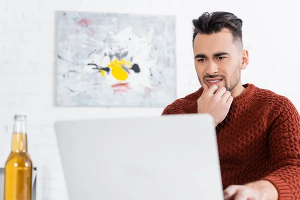 Worried Bookmaker Looking Laptop Blurred Bottle Beer — Φωτογραφία Αρχείου