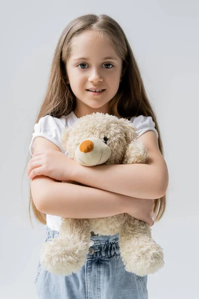 Compiaciuta Ragazza Abbracciando Orsacchiotto Mentre Guarda Fotocamera Isolata Sul Grigio — Foto Stock