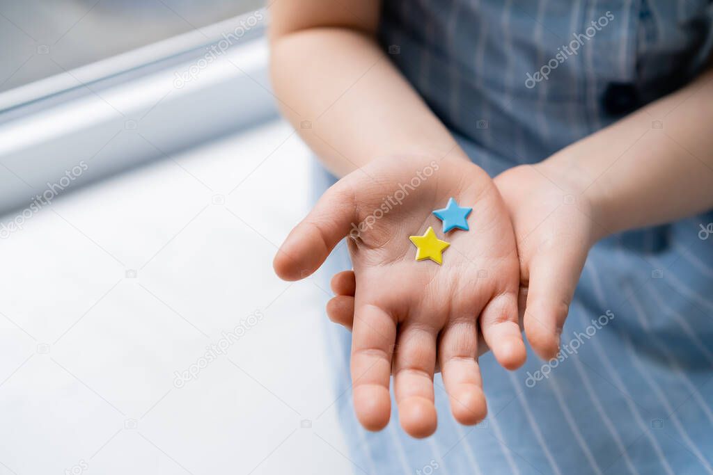 partial view of child with blue and yellow stars on open palm
