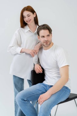 Genç adam beyaz tenli neşeli kız arkadaşının yanında oturuyor. 