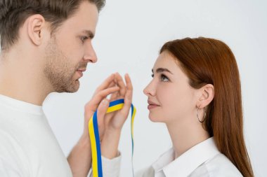 Mavi ve sarı kurdeleli genç çiftin beyaz üzerine izole edilmiş görüntüsü 