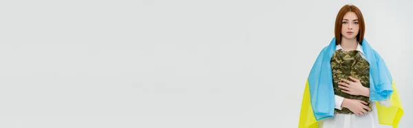 Молода жінка в українському прапорі обіймає військову форму, ізольовану на білому прапорі. — стокове фото