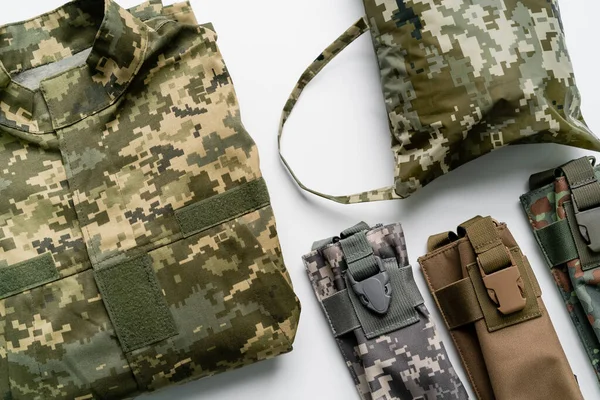 Top view of military uniform and bags on white background