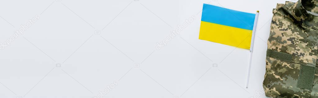 Top view of ukrainian flag near military uniform on white background, banner 