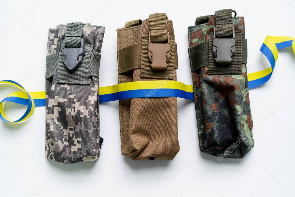 Top view of blue and yellow ribbon on military bags on white background