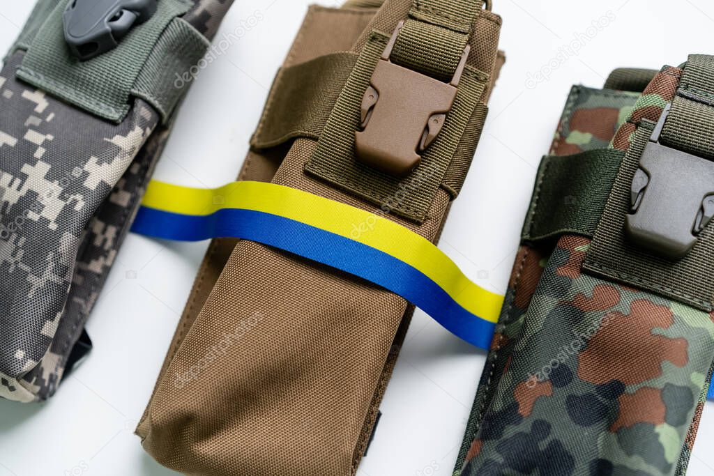 Top view of blue and yellow ribbon near military bags on white background