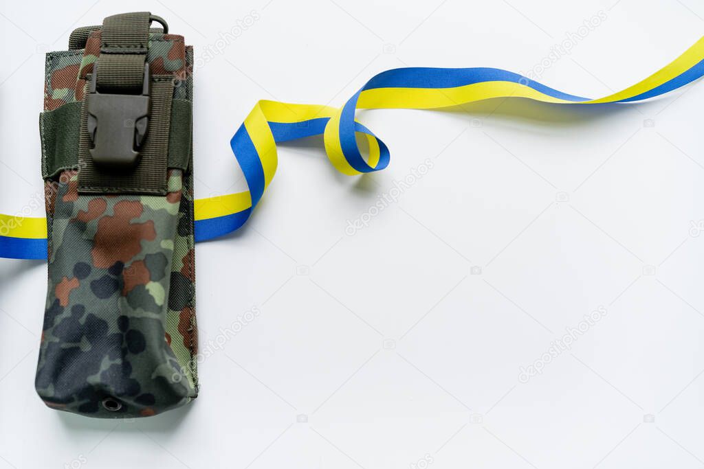 Top view of blue and yellow ribbon near military bag on white background