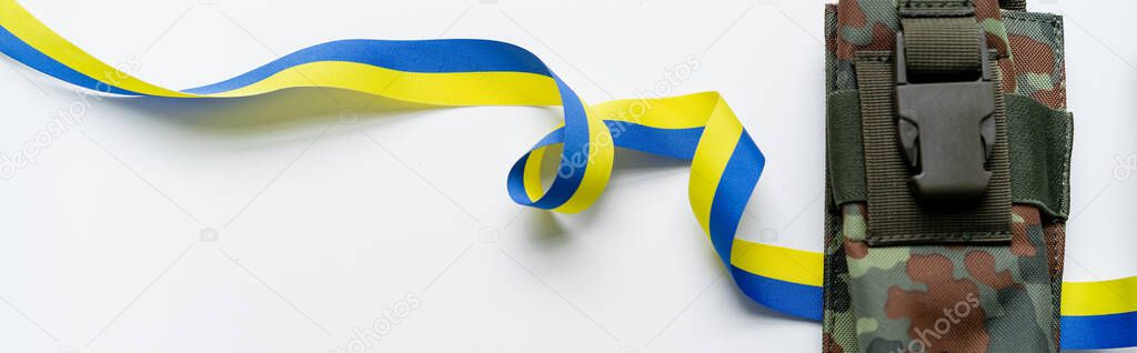 Top view of blue and yellow ribbon near military bag on white background, banner 