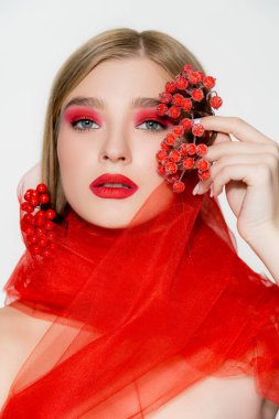 Makyajlı bir model ve beyaz böğürtlen tutan kırmızı bir bez.