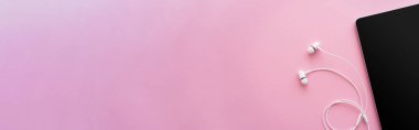 Pembe kulaklıkların yanında boş ekranı olan dijital tabletin üst görünümü, afiş