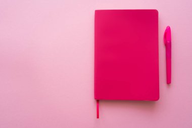 Pembe üzerine parlak defter ve kalem görünümü 