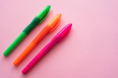 Pembe üzerine renkli ve parlak kalemlerin üst görünümü 