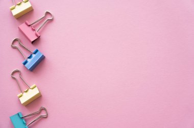 flat lay of colorful pastel fold back clips on pink