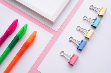 high angle view of colorful stationery on white papers on pink