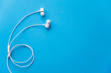 top view of white wired earphones on blue