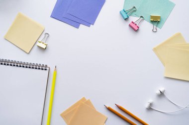 Boş defter ve kulaklıkların beyaz kağıdın yanındaki üst görünümü