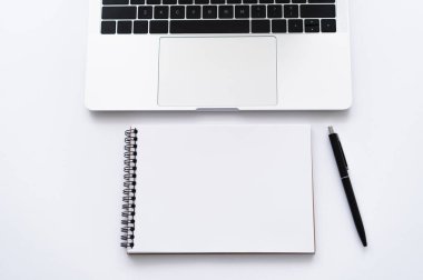 top view of notebook and pen near modern laptop on white