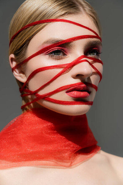Fair haired model with red threads and visage looking away isolated on grey 