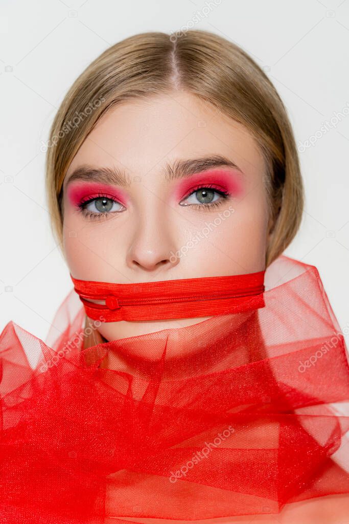 Young woman with red zipper on mouth and tulle cloth isolated on grey 