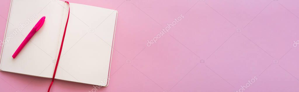 top view of empty open notebook and pen on pink, banner